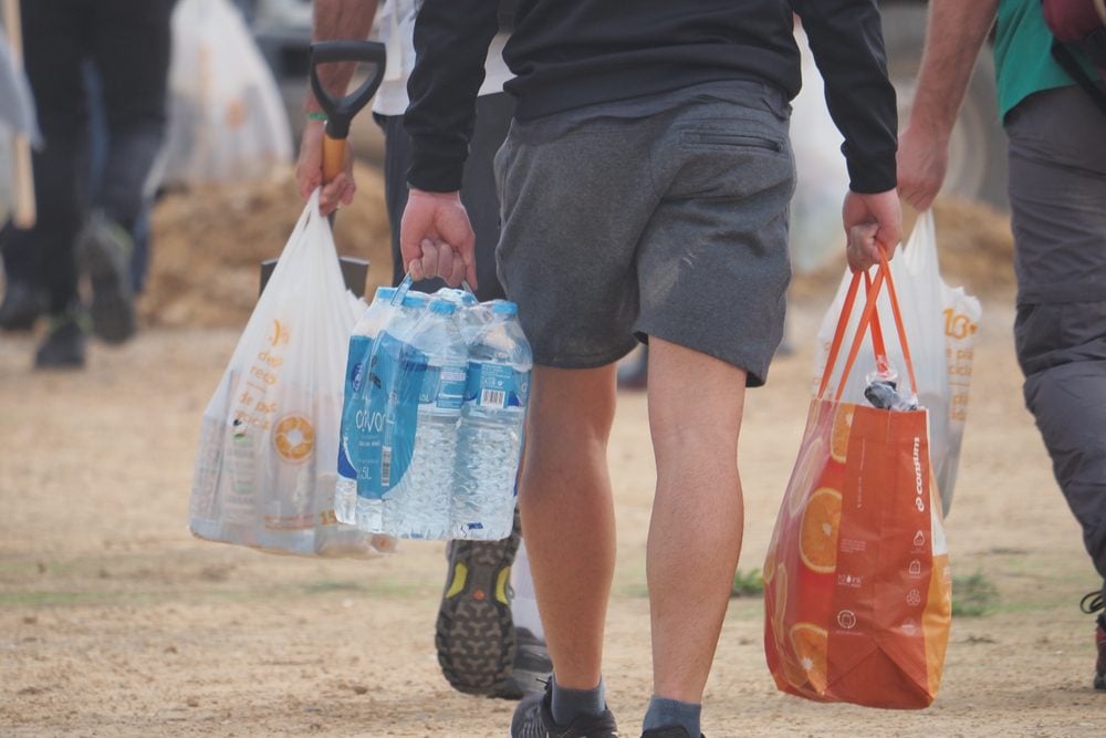 Volunteers carrying water bottles and food in plastic bags