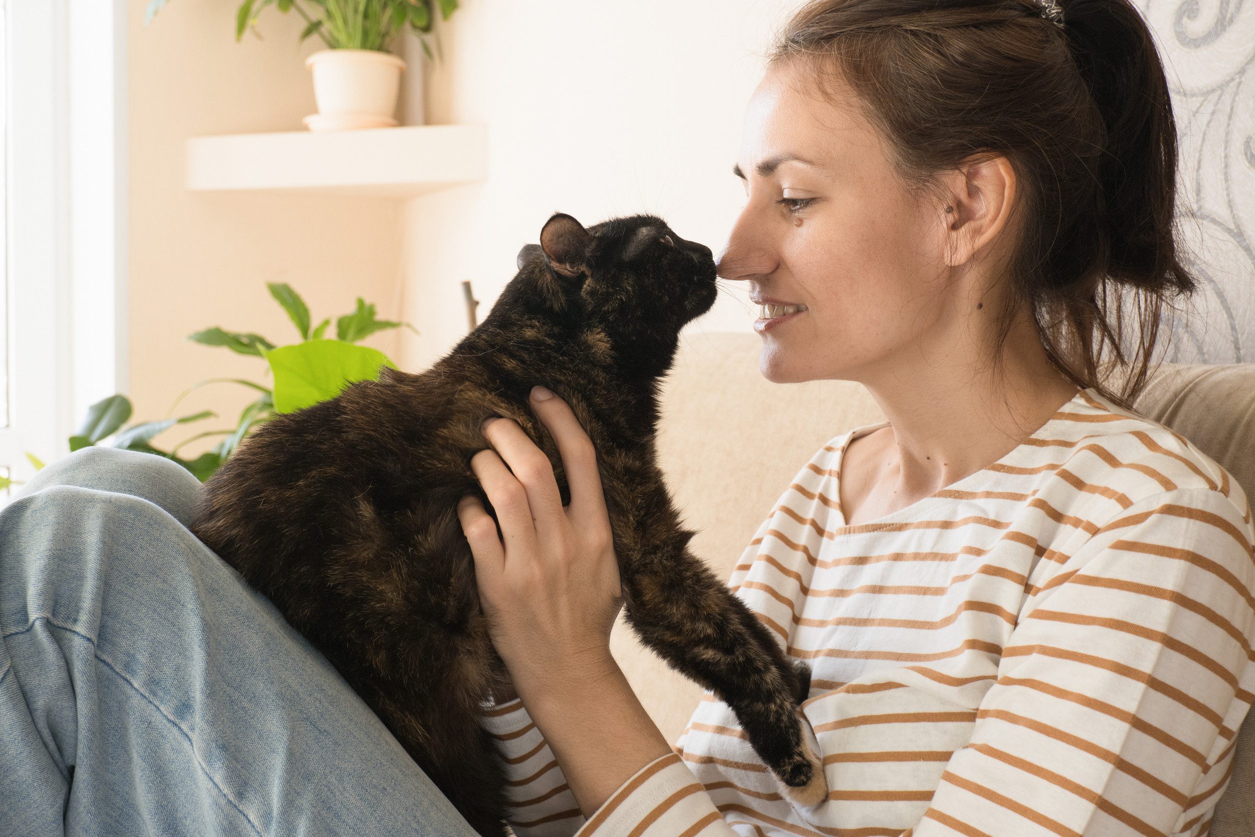 A woman holding her emotional support animal while sitting in bed in her home in Kahului, HI.