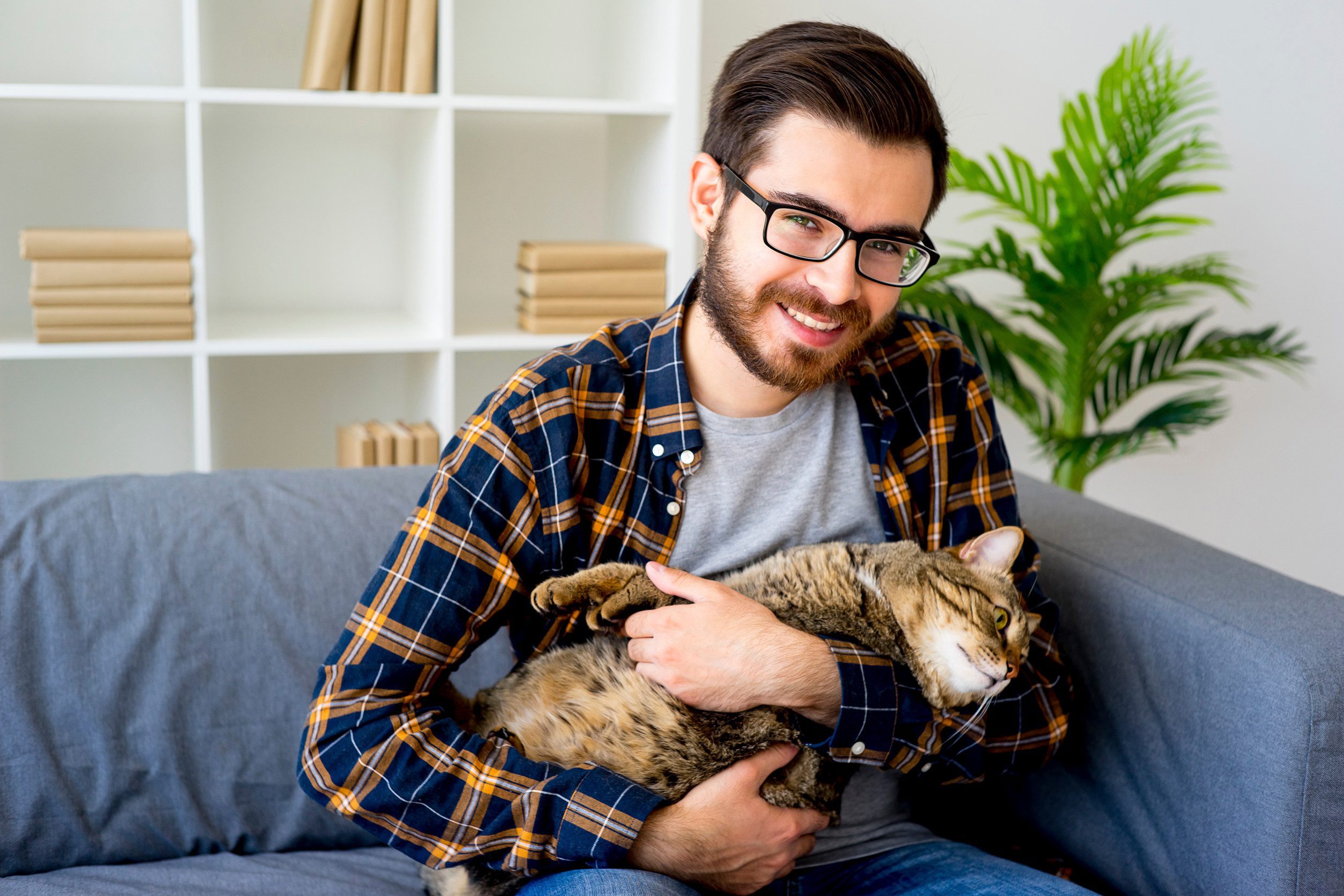 A man in a blue checkered shirt, smiling at the camera, while holding his emotional support animal (ESA) in Southaven, MS.