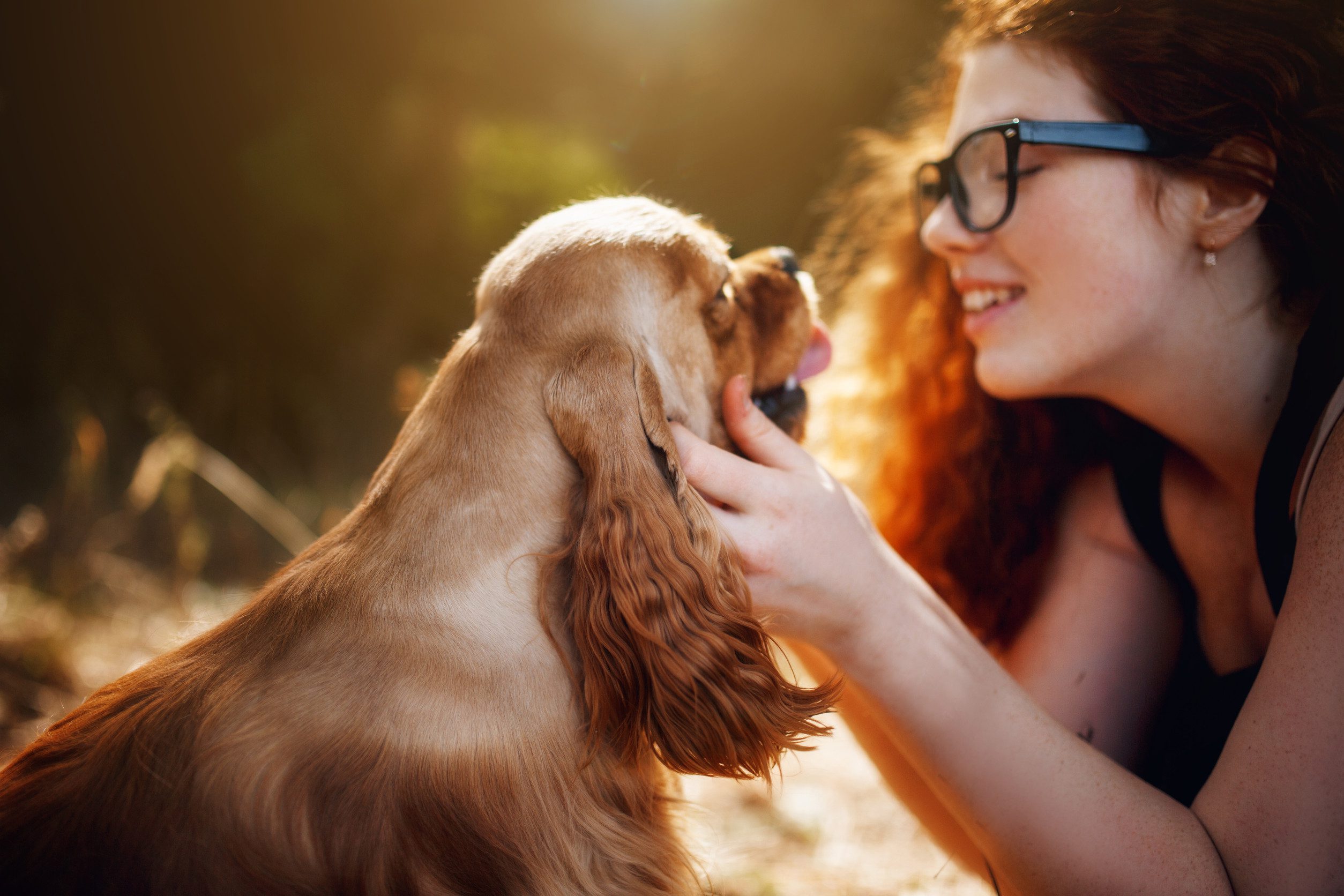 A young woman gazing affectionately at her emotional support animal in a park in Des Moines, IA.