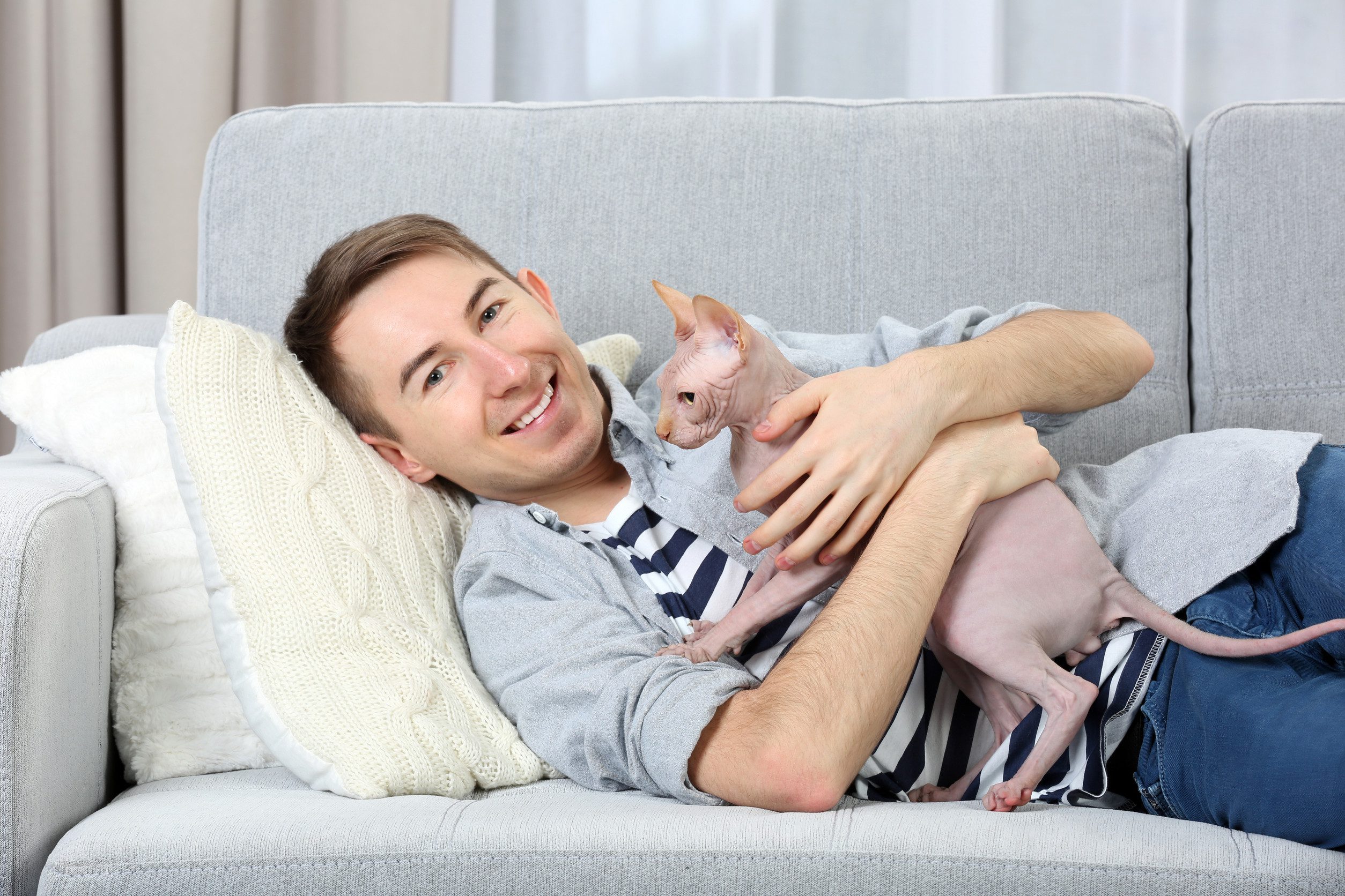 A young man relaxing on a couch while happily holding his emotional support animal in Erie, PA.