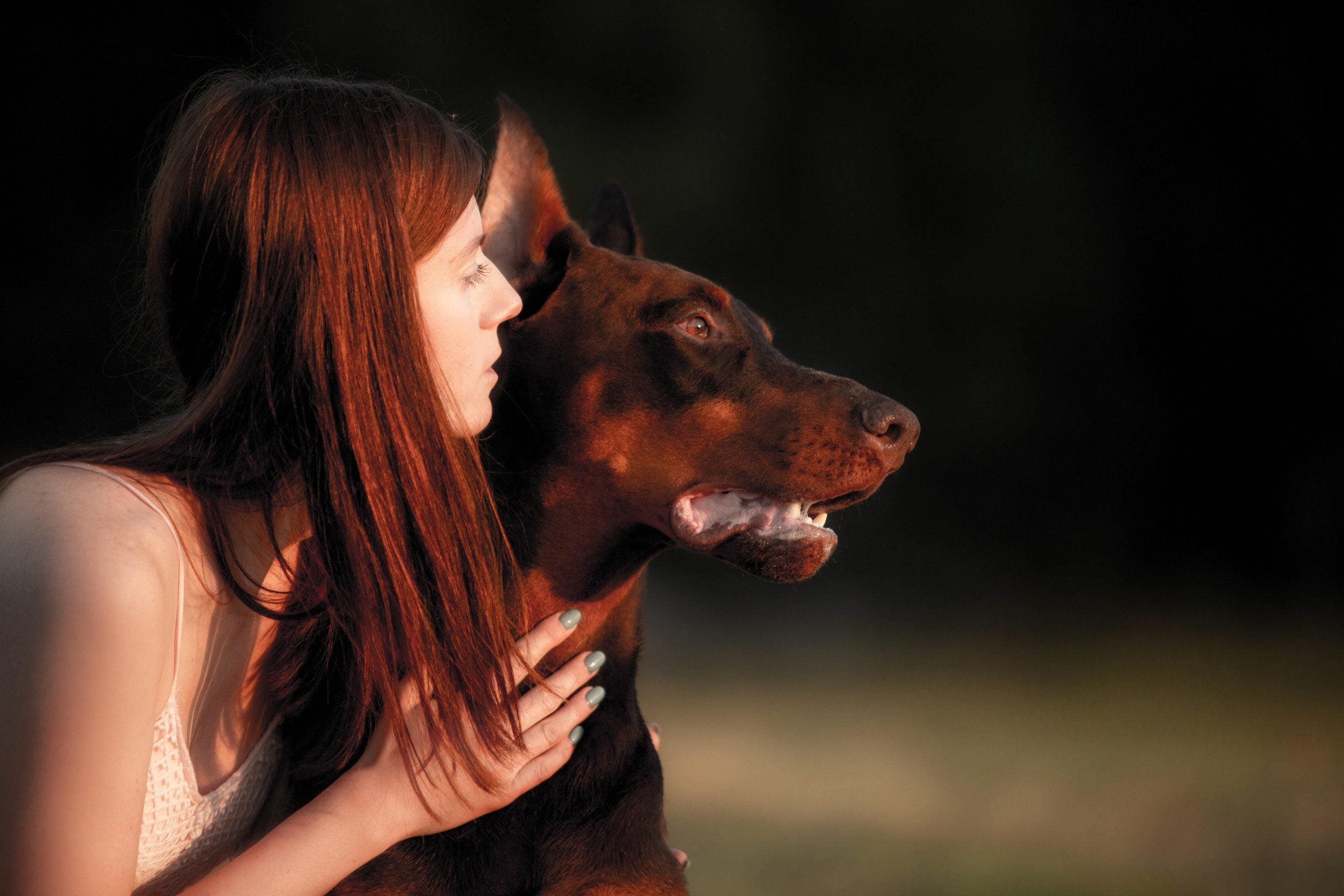 A woman holding her emotional support animal Doberman outdoors in Greensboro, wondering how to get an ESA letter in Greensboro.