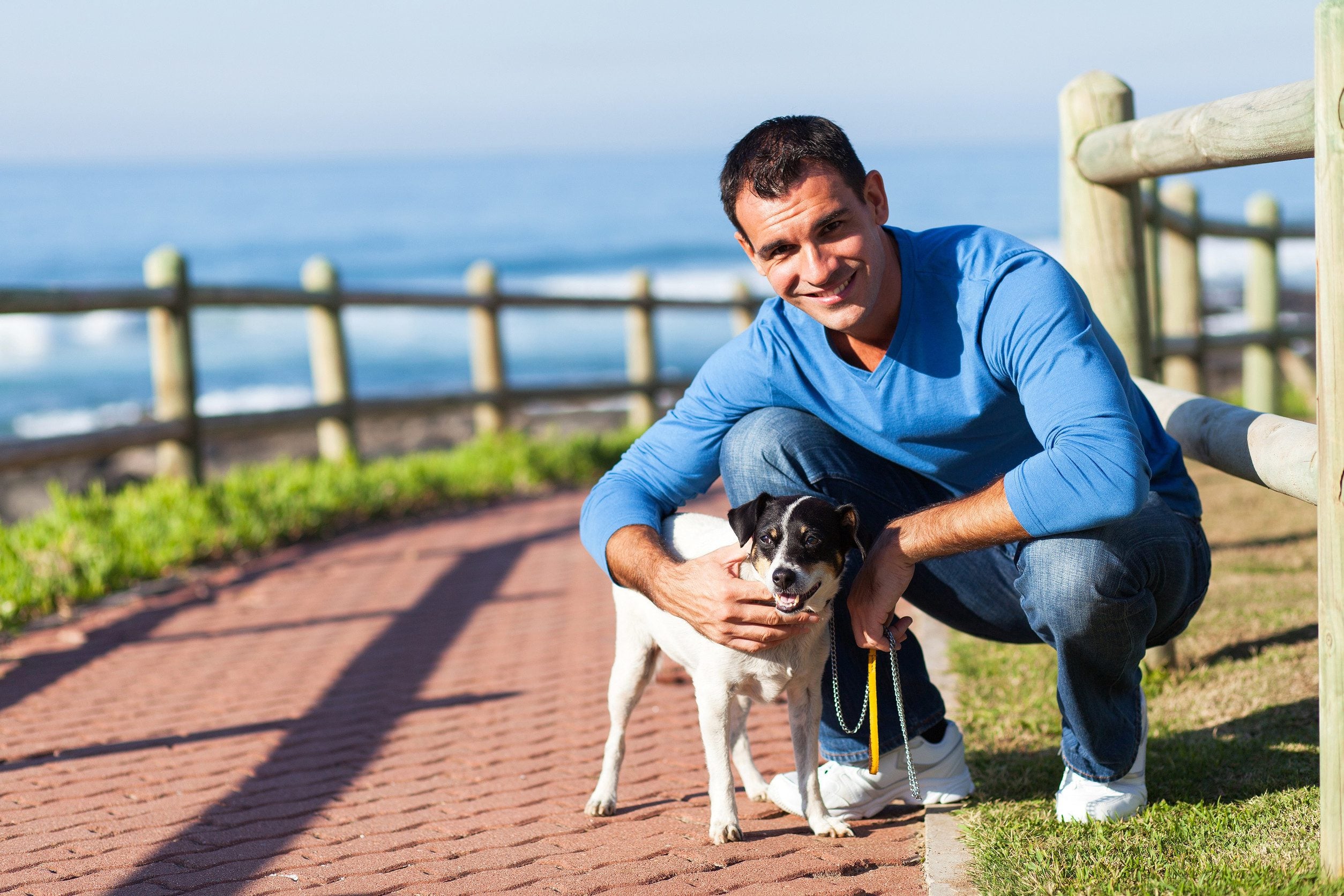 A man crouching next to his emotional support animal while walking in Cranston, RI.