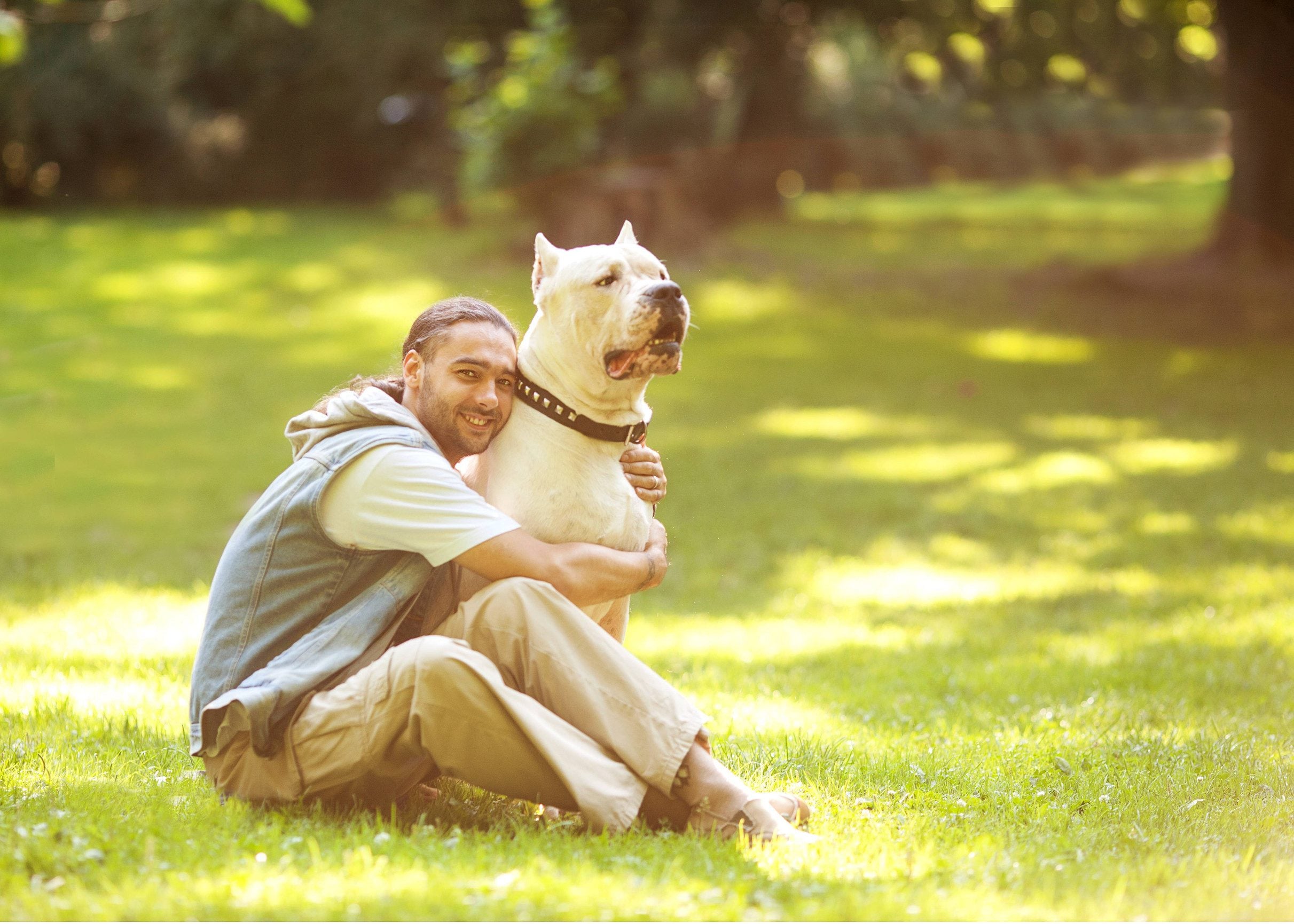 A man sitting in a park hugging his emotional support animal in Paterson, NJ.
